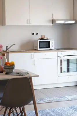 a white kitchen with a table and a microwave at Venetian Owl, 1min To Lighthouse in Chania Town