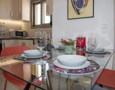 a glass table with plates and wine glasses on it at A Heaven View Park Hideaway - Chania Nest in Chania Town