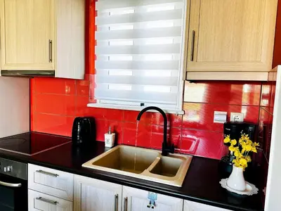 a kitchen with a sink and a red wall at Cozy Snuggle- 2min To Beach, 6min Walk To Old Town in Chania Town