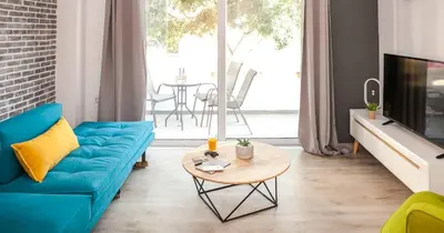 a living room with a blue couch and a table at Secret Loft, 2min Walk From The Beach, High Tech in Chania Town
