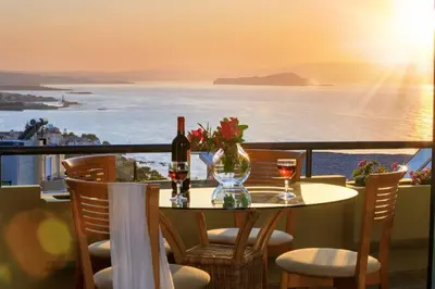 a table with two glasses of wine and a view of the ocean at Koralia - Chanias Card Postal Villa Majestic View in Chania Town