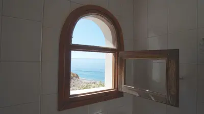 a window in a bathroom with a view of the ocean at Ilingas Hotel in Khóra Sfakíon