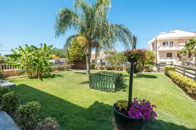 a yard with a palm tree and flowers at Armeria Apartments in Daratso