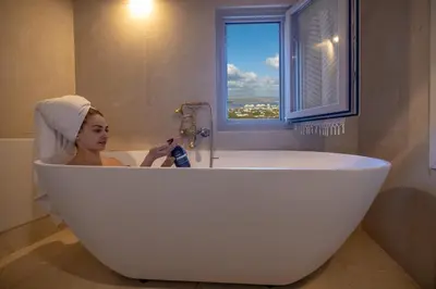 a woman sitting in a bath tub with a towel on her head at Rimondi Residences Chania in Chania Town