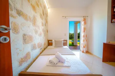 two beds in a room with a stone wall at Villa Lima Pool & Jacuzzi Chania in Vamos