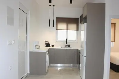 a white kitchen with a sink and a refrigerator at Camelia Home in Chania Town