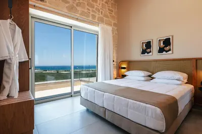 a bedroom with a large bed and a large window at Petras Luxury Villas in Falasarna
