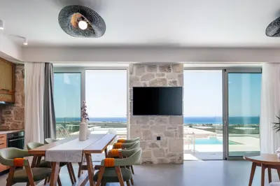 a living room with a table and chairs and a television at Petras Luxury Villas in Falasarna