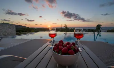 two glasses of wine and a bowl of fruit on a table at Petras Luxury Villas in Falasarna