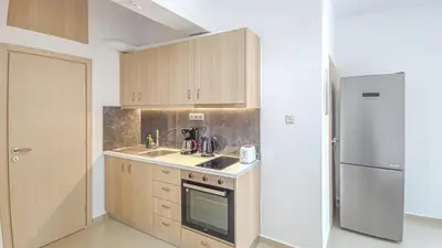 a kitchen with wooden cabinets and a refrigerator at Fully renovated Studio in Platanias in Plataniás