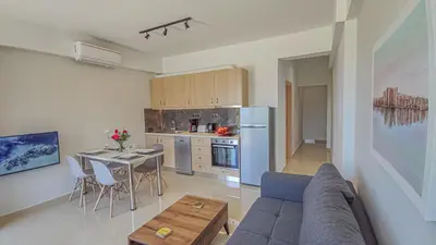 a living room with a couch and a table and a kitchen at Fully renovated apartment in Platanias 1 in Plataniás