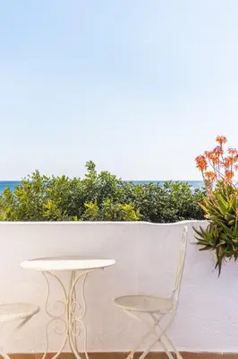 a table and a chair on a balcony with the ocean at Babis & Popi Rooms and Studios in Frangokastello