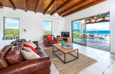 a living room with a leather couch and a table at Villa Vereniki in Áyios Andhréas