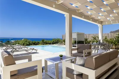 a patio with chairs and a swimming pool at ALKI VILLAS COLLECTION -LUXURY SEA VIEW VILLAS - BREAKFAST INCLUDED- Falasarna in Falasarna