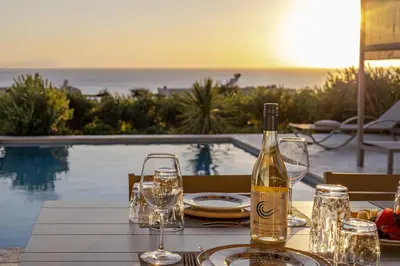 a bottle of wine sitting on a table with glasses at ALKI VILLAS COLLECTION -LUXURY SEA VIEW VILLAS - BREAKFAST INCLUDED- Falasarna in Falasarna