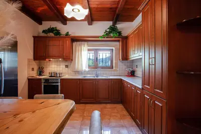 a kitchen with wooden cabinets and a wooden table at Kotinos Luxury Villa in Chania Town