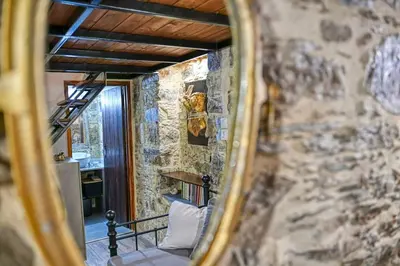 a mirror reflection of a room with a stone wall at PefkoPetro Loft in Chania Town