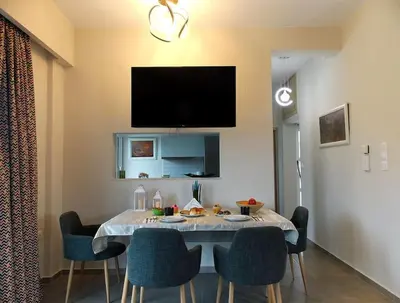 a dining room table with chairs and a tv on the wall at Alena home in Chania Town