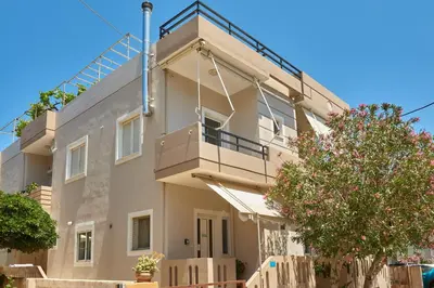 a white building with a balcony and a tree at Luxurious house near the sea in Kato Daratso