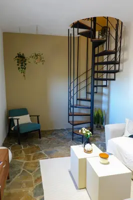 a living room with a spiral staircase and a couch at almond home in Livadia
