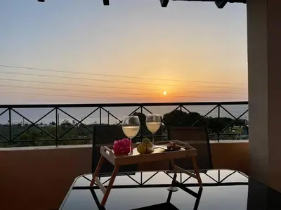 a table with two glasses of wine on a balcony at almond home in Livadia