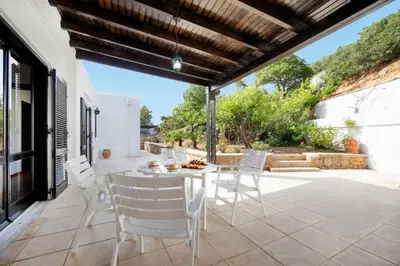 a patio with a white table and white chairs at Casa Bella Vista in Kalathas