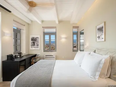 a bedroom with a bed and a desk and windows at La Torre del Kastelli in Chania Town