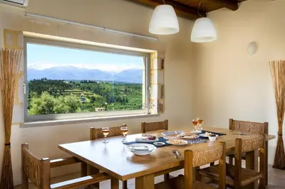 a dining room with a table and a large window at Villa Asteriskos in Áyios Andhréas