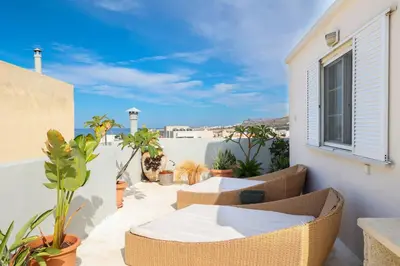 a balcony with wicker chairs and tables on a building at Chania Locals Rooftop in Chania Town