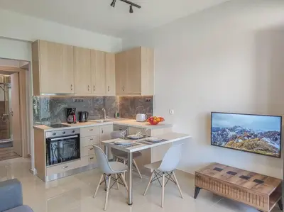 a kitchen with a table and chairs and a tv at Renovated apartment 2 -Platanias in Plataniás