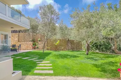 a backyard with a lawn with trees and a fence at Renovated apartment 2 -Platanias in Plataniás