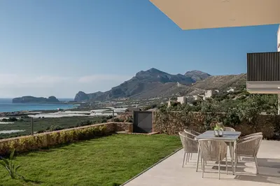 a patio with a table and chairs and a view of the ocean at GG Villas Falassarna in Chania Town