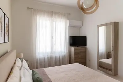 a white bedroom with a bed and a television at Casa Valore central with parking by 8essentially in Chania Town