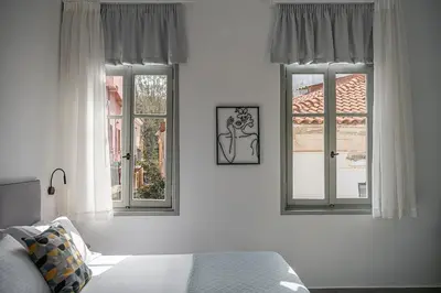 a bedroom with two windows and a bed at Porto Vecchio in Chania Town