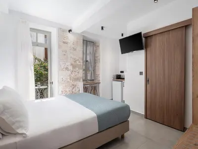 a bedroom with a bed and a tv on a wall at Porto Vecchio in Chania Town