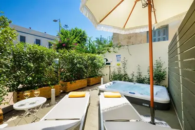 a hot tub in a courtyard with chairs and an umbrella at Casa Verde Chania in Chania Town