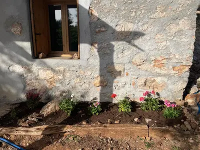 a shadow of a window on a stone building with flowers at Petres old village house in Áyios Ioánnis