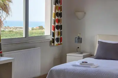 a bedroom with a bed and a window with the ocean at Mabech Villa in Plataniás