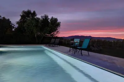 a pool with chairs and a table with a sunset at Mabech Villa in Plataniás