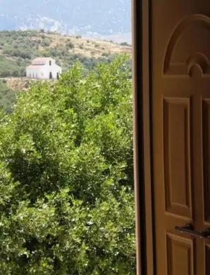 a window with a view of a white barn and trees at VILLA APHRODITE SOUGIA apt1 in Kamária