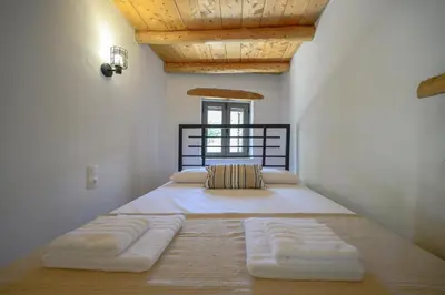 a large bed with white sheets and pillows in a room at Nomas Home Imbros in Khóra Sfakíon
