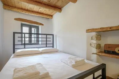 a bedroom with a bed with white sheets and towels at Nomas Home Imbros in Khóra Sfakíon