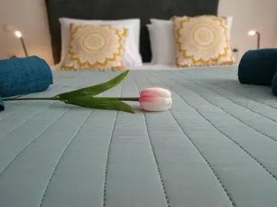 a white bed with a pink flower on it at StelisIoanna in Chania Town