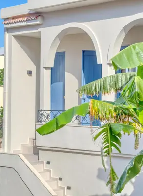 a white house with blue windows and a palm tree at Il Porto Blu in Chania Town