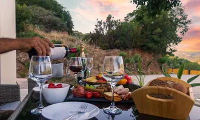 a man is pouring wine into glasses on a table at Archontissa Kakodiki - Paleochora in Áyioi Theódhoroi
