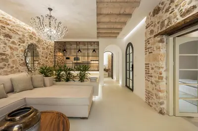 a living room with a stone wall and a chandelier at il Campanile Luxury Living in Chania Town