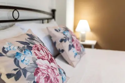a bed with floral pillows on it with a lamp at Helios studio next to the sea BY APOKORONAS-VILLAS in Kalyves