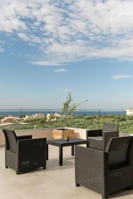a patio with a table and chairs and a view of the ocean at Oliva Verde Residences in Galatás