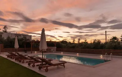 a swimming pool with lounge chairs and a umbrella at Oliva Verde Residences in Galatás