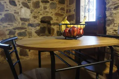 a wooden table with a bowl of fruit on it at Rosales stone house in AmigdhalokeFálion